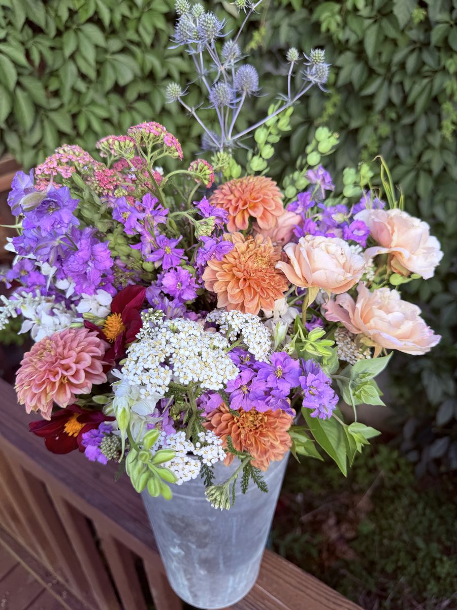 Bouquet of colorful flowers in a clear vase against a green foliage background